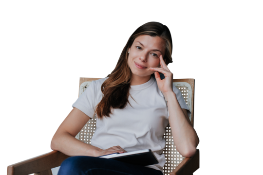 Confident brunette woman in white t-shirt and blue jeans sits on chair with laptop leaning on hand looks at camera against transparent background. Satisfied Spanish woman with loose hair relaxing home