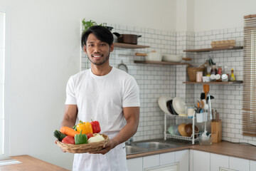 Handsome asian man cooking at home preparing salad in kitchen.