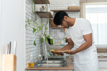Asian man washing dishes at kitchen in morning.