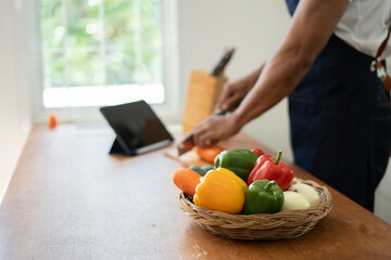 Handsome asian man cooking at home preparing salad in kitchen.