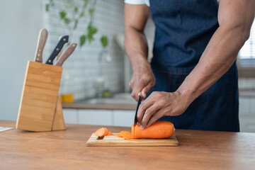 Handsome asian man cooking at home preparing salad in kitchen.