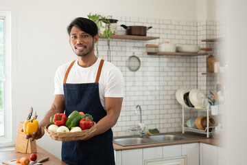Handsome asian man cooking at home preparing salad in kitchen.