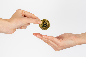 woman's hand giving a bitcoin coin to another woman