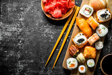 Variants of types of sushi, maki and rolls on a cutting Board with ginger and soy sauce.