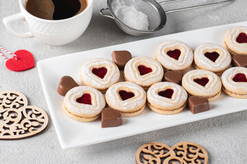 Homemade shortbread with raspberry jam heart-shaped filling and chocolate candies hearts on white...