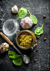 Pesto sauce in a glass jar with garlic and herbs.