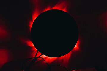 black frying pan in the dark under which red lights are lit.