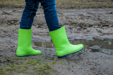 rubber boots of green color in the mud. Rubber boots of green color on a dirt road. Dirty...