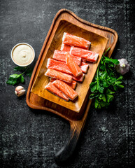 Crab sticks on a cutting Board with greens, sauce and garlic.
