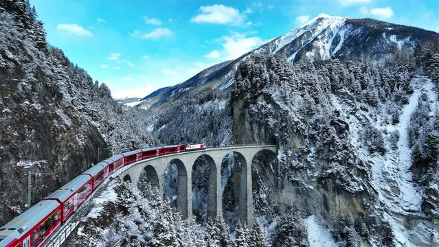Aerial view of Train passing through famous mountain in Filisur, Switzerland. Landwasser Viaduct world heritage with train express in Swiss Alps snow winter scenery. 