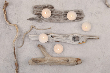 Sea driftwood pieces and tea light candles on stone background. Pieces of sea drift wood, top view....