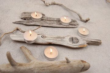 Sea driftwood pieces and tea light candles on stone background. Pieces of sea drift wood. Bleached dry aged drift wood.
