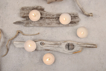 Sea driftwood pieces and tea light candles on stone background. Pieces of sea drift wood, top view....