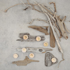 Sea driftwood pieces and tea light candles on stone background. Pieces of sea drift wood, top view. Bleached dry aged drift wood.