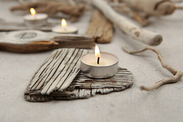 Sea driftwood pieces and tea light candles on stone background. Pieces of sea drift wood. Bleached dry aged drift wood.