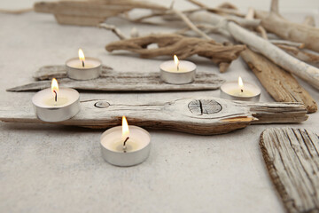 Sea driftwood pieces and tea light candles on stone background. Pieces of sea drift wood. Bleached...