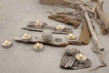 Sea driftwood pieces and tea light candles on stone background. Pieces of sea drift wood. Bleached...
