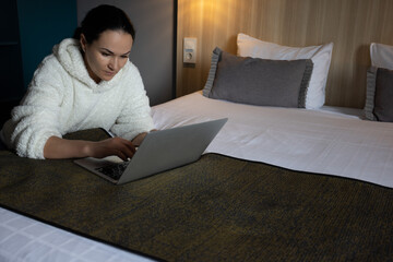 Woman on a bed busy behind laptop. Serious woman working or studying at home behind laptop till...