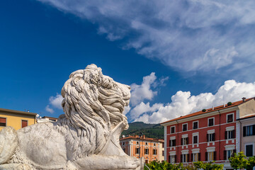 One of the marble lions in Piazza Aranci square, Massa, Italy, on a sunny day