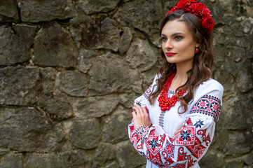 Portrait of a beautiful Slavic girl with long blond hair and blue eyes with a flower crown in a white and red embroidered dress with a bouquet. Traditional clothes of the Ukrainian