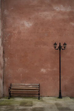 Empty bench and street lamp standing in front of weathered pink wall , blank space for text , retro background
