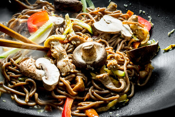 Fototapeta premium Delicious Chinese soba wok noodles with beef, mushrooms and vegetables.