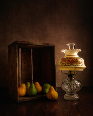 Collection of Yellow and Green Pears arranged in an Antique Wooden Apple Box lit by an Antique Hurricane Lamp
