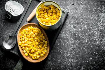 Open tin can with canned corn on the cutting Board.