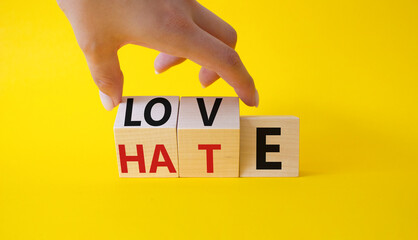 Love vs Hate symbol. Businessman Hand turns cubes and changes word Hate to Love. Beautiful yellow background. Valentines day and Love vs Hate concept. Copy space