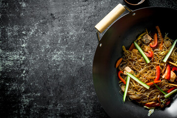 Chinese wok. Asian cellophane noodles with vegetables and chicken in a frying pan wok.