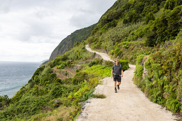 Hiker coming down a hiking trail on the southeast coast of São Jorge island, Azores