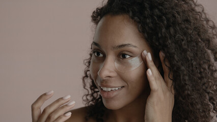 CU Portrait of attractive African-American female doing her skincare routine. Applying eye patches....