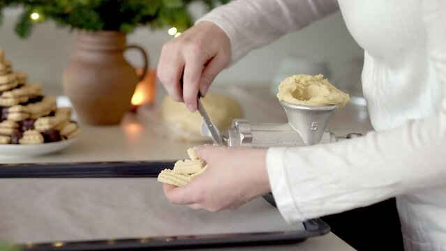 Preparation of handmade Christmas pastry - cutting dough pressed through a mincer