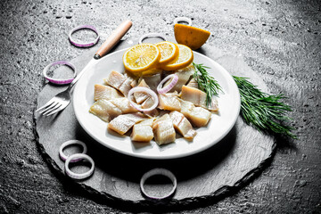 Fillet of salted herring with slices of lemon, onion and herbs.