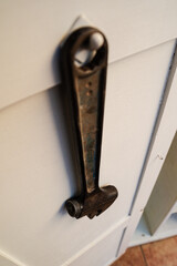 Llave inglesa de gran tamaño colgada de puerta de armario de herramientas.