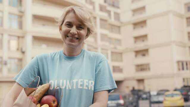 Portrait of smiling woman volunteer with grocery bag, charity, social services