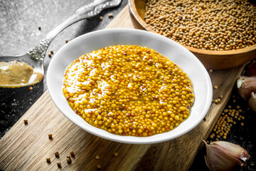 Mustard on a cutting Board with garlic cloves.