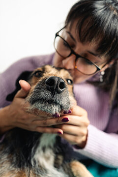 Latin woman kissing her dog in the head with love. Vertical photography close up image