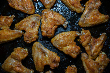 Top view of crispy chicken wings on a black baking sheet 