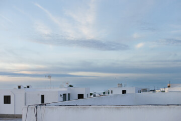 Pastel pale blue sunrise with clouds  and white silhouettes of the residential buildings at Lanzarote island. Landscape of Canary Islands typical white color painted houses. Real estate business.