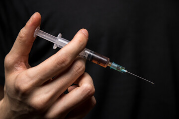 Close-up of a hand holding a heroin syringe. Drug addiction concept
