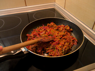 A person preparing a traditional Serbian dish - Przenija, paprika fried in oil, close up shot