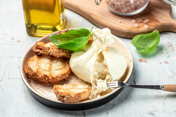 Italian burrata cheese, white balls of burrata or burratina cheese Basil and Olive Oil and Ciabatta. place for text, top view