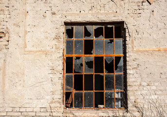 Window with broken glass on an old wall.