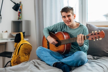 Teenage boy practices the guitar