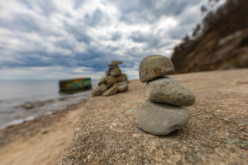 Small pile of small stones lying on giant rock at the edge of beach next to Baltic sea