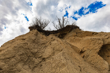 Looking up to high sandy and stony cliff next to the beach