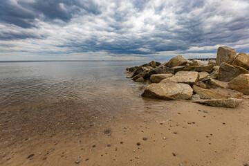 Small pile of huge rocks lying at the coast of Baltic sea next to beach