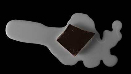 Spilled milk puddle with pieces of chocolate isolated on black with clipping path, top view