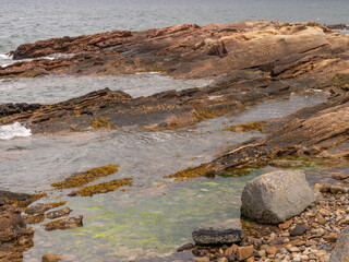 impressive rock formations and waves at Portmahomack beach in summer, Highland scotland, UK